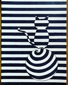 a cat sitting on top of a ball in the middle of a striped wallpaper