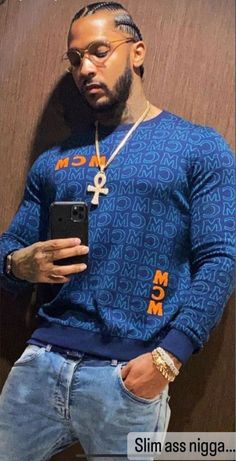 a man standing in front of a wall holding a cell phone