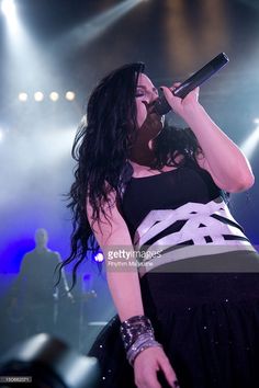 a woman in black and white dress singing into a microphone on stage at a concert