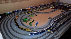 a toy train track with cars and trains on it in the middle of a room