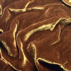 a close up view of a brown and gold colored blanket with some folds on it