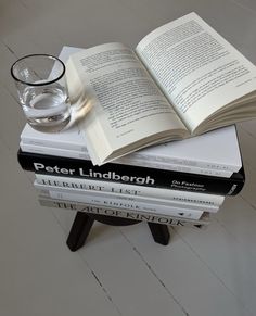 a stack of books sitting on top of each other next to a glass filled with water