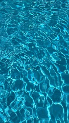 the blue water is reflecting light on it's surface and ripples in the pool