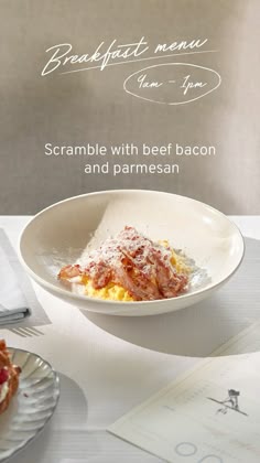 a white bowl filled with food on top of a table next to other plates and utensils