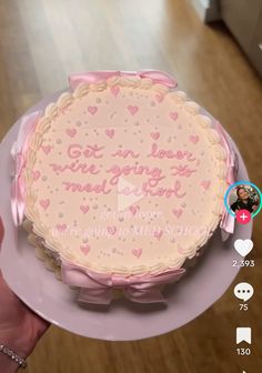 a cake with pink frosting and hearts on the top is being held by someone