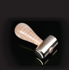 a close up of a metal object with a wooden handle on a black surface in the dark