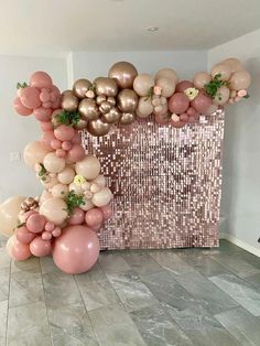 balloons and greenery are arranged on the floor in front of a large balloon wall
