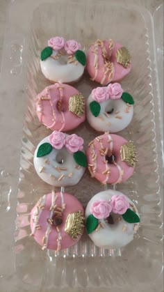 cupcakes with pink frosting and gold decorations on them in a plastic tray