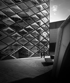black and white photograph of two people standing in front of a large building with many windows