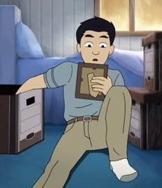 a man sitting on the floor in front of a bed holding a box with his hand