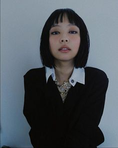 a young woman with black hair and bangs wearing a black shirt is posing for the camera
