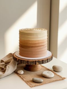 a cake sitting on top of a wooden stand next to some white and brown rocks
