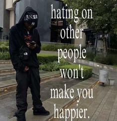 a man in black hoodie texting on his cell phone while standing on steps