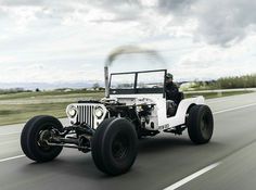 an old white jeep driving down the road