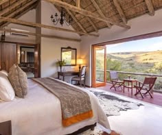 a bedroom with a large bed sitting under a thatched roof next to a patio