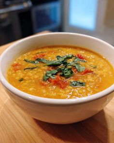a white bowl filled with soup on top of a wooden table