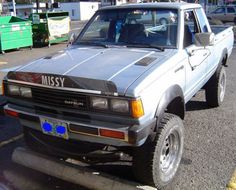 the truck is parked on the side of the road near other cars and trucks in the parking lot