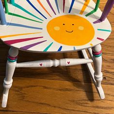 a child's wooden chair painted with multicolored sticks and smiley face on the seat