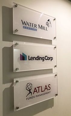 three glass signs mounted on the side of a wall in an office building that says lending corp, atlas and water mill