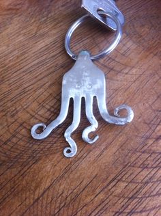 an octopus shaped metal keychain sitting on top of a wooden table