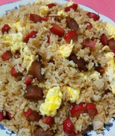a plate with eggs, sausage and rice on it sitting on a pink table cloth