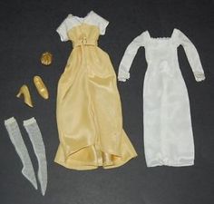 an assortment of doll clothes and accessories are laid out on a black surface, including a white dress