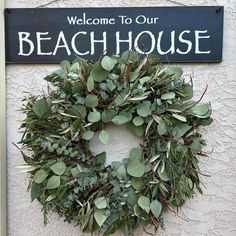 a welcome to our beach house sign hanging on the side of a building with a wreath