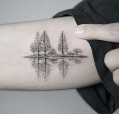 a woman's arm with trees and water on it