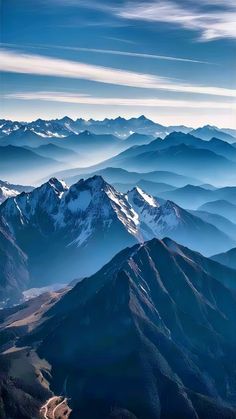 an aerial view of mountains and valleys in the distance, with blue sky above them