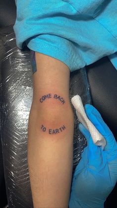 someone with a tattoo saying come back to earth