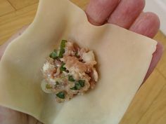 a hand holding a small piece of food in it's left hand on top of a wooden table