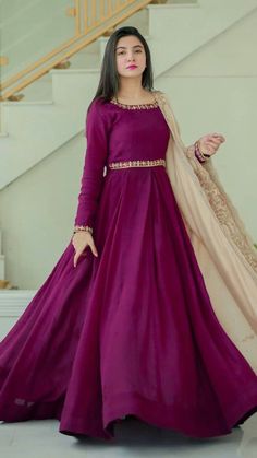 a woman in a long purple dress standing on the stairs with her hand on her hip