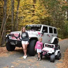a woman and her daughter standing next to a jeep