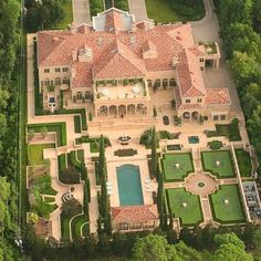 an aerial view of a large mansion surrounded by lush green trees and bushes, with a pool in the middle