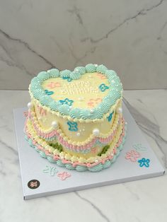 a heart shaped cake sitting on top of a white table next to a blue and pink card