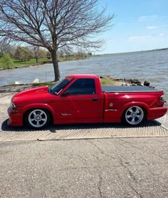 a red pick up truck parked next to the water