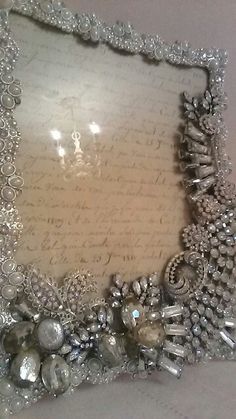 an ornate silver frame with pearls and jewels on it's sides, sitting on a table