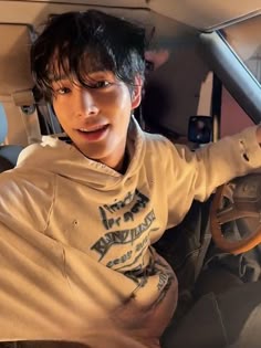 a young man sitting in the driver's seat of a car