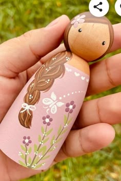 a hand holding a small wooden doll in it's palm