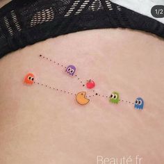 a woman's stomach with pacman and apple tattoos on the side of her belly