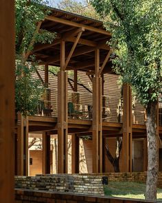 a large wooden structure sitting on top of a lush green field next to a tree