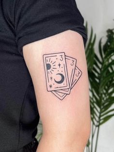 three playing cards tattoo on the left upper half of the arm, with stars and moon