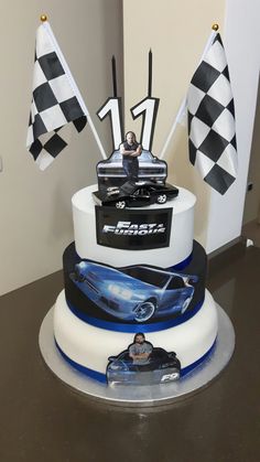 a car themed birthday cake with flags on the side and a race car figurine sitting on top