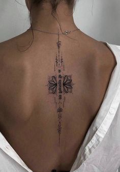 the back of a woman's neck with an intricate cross tattoo on her left shoulder