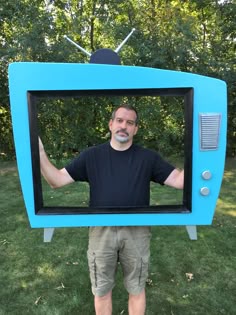 a man standing in front of a blue tv with his hands on the television screen