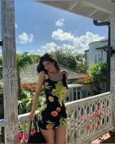 a woman is standing on a porch holding a handbag