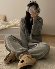 a woman sitting on the floor taking a selfie with her phone and wearing headphones