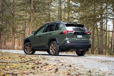 a green jeep parked on the side of a forest road