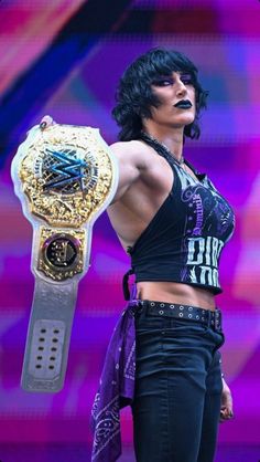 a female wrestler holding a wrestling belt on stage