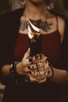 a woman holding a candle in her hands with flames coming out of the top and bottom